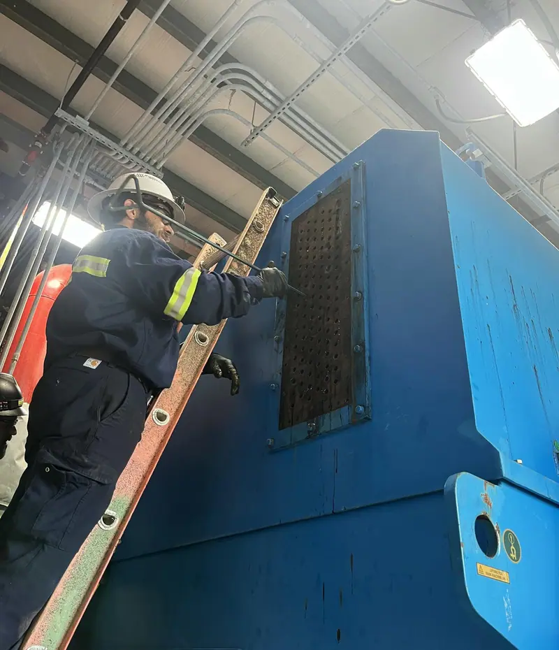 Technician on a ladder working on a large blue generator enclosure